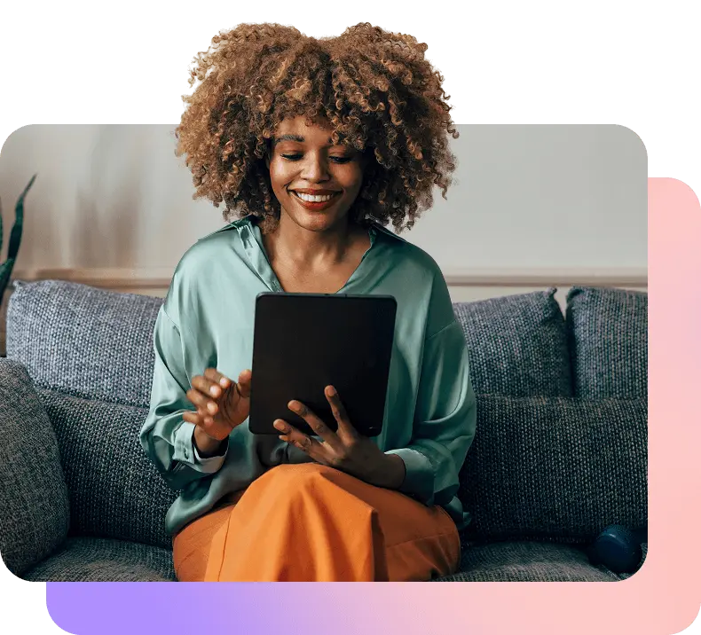 Woman sitting on a couch smiling and looking at a tablet. There is also a light gradient shaped off-center behind the shot of the woman.