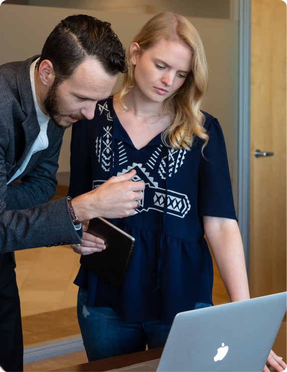 Two people having a discussion around a laptop.