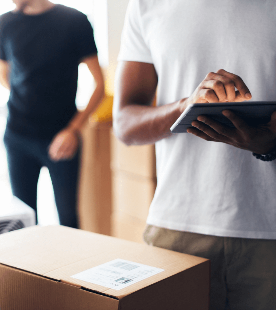 Man looking at box and using a tablet.