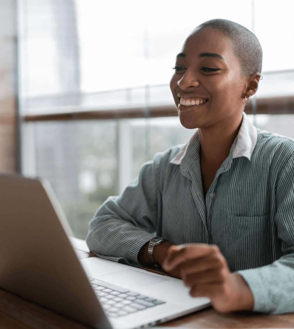 Woman at desk smiling at laptop.