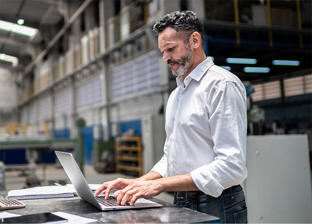 man in a warehouse using a laptop.