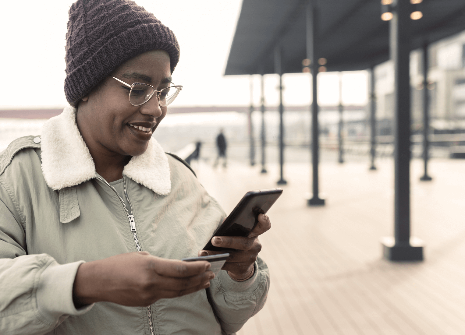 Woman outdoors typing a card number into her phone.