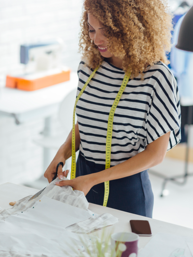 Woman with measuring tape cutting fabric.